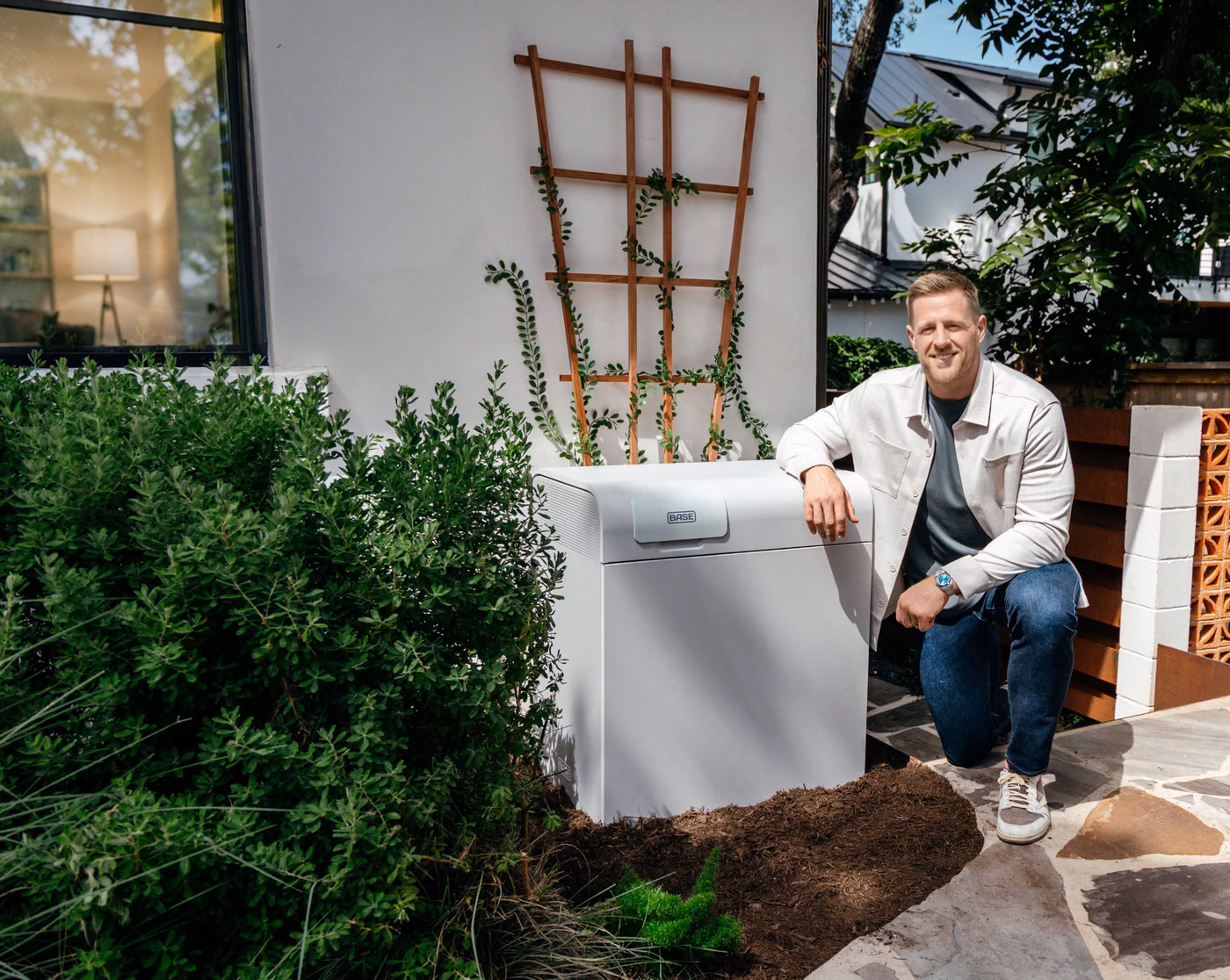 JJ Watt kneeling beside the Base battery installed at his home