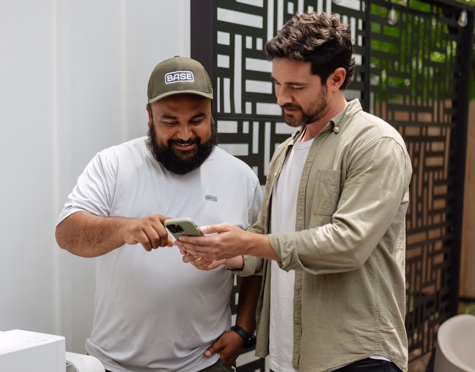 A Base Power team member and a homeowner reviewing home photos on a phone