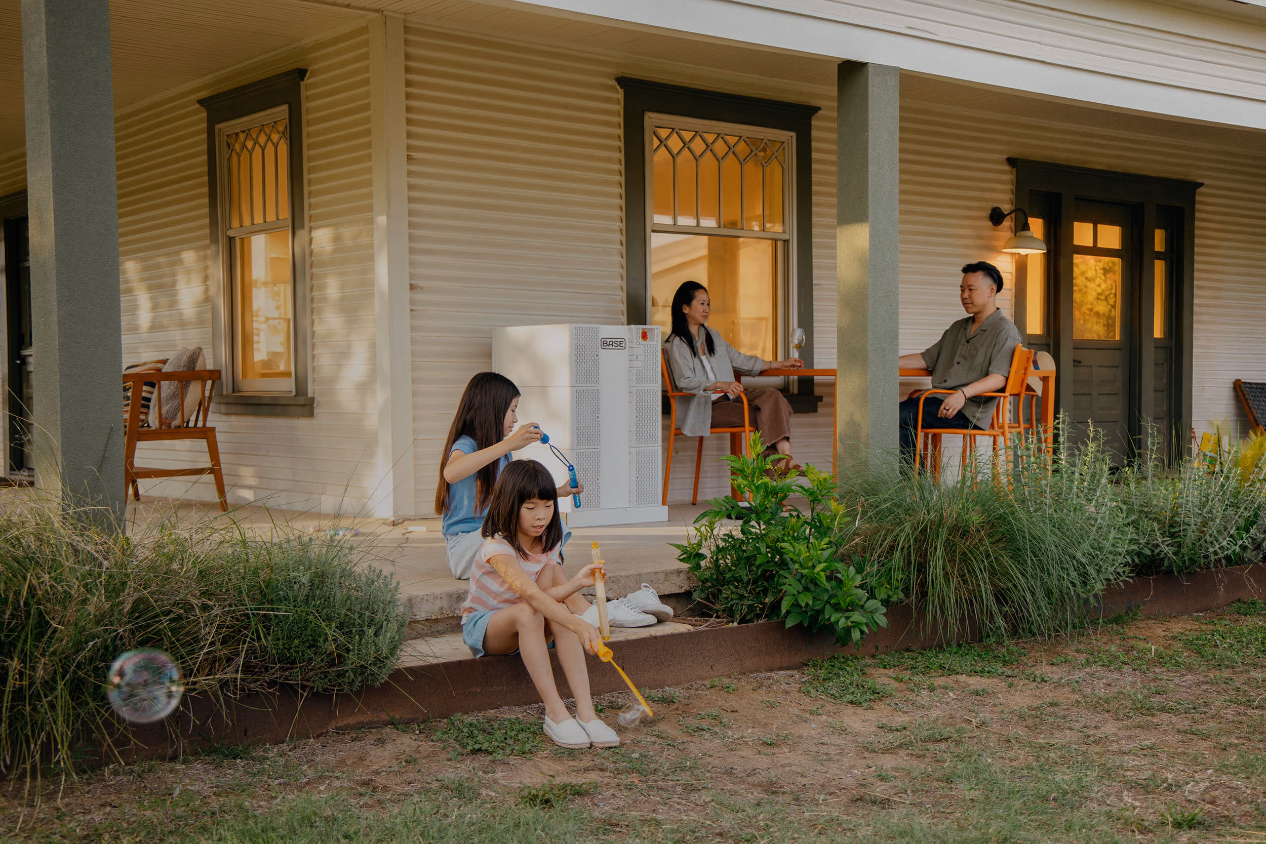 A family relaxing outside their home with a Base Power battery