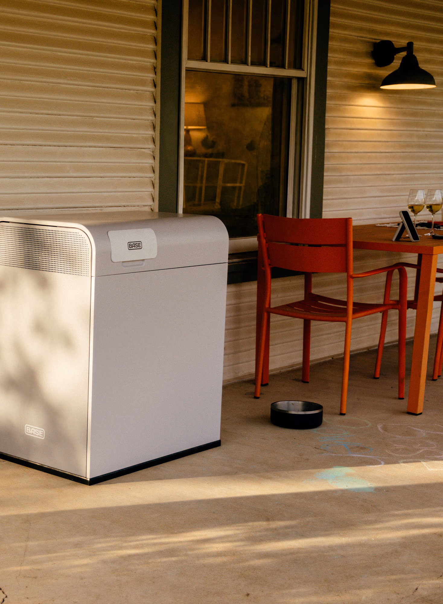 A Base Power battery on a porch beside an outdoor dining setup